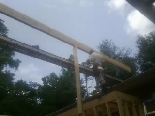 Carpenter setting a ridge beam over a new addition frame — Ice Dam Removal by Roofing Brothers in Corsicana