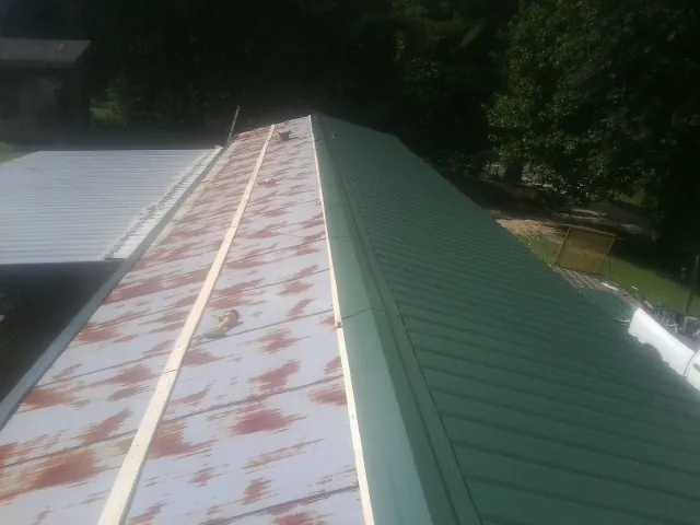 Old rusted panels beside newly installed green metal roofing — Wind Damage Roof Repair by Roofing Brothers in Corsicana