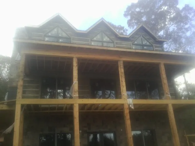 Dormers and porch framing on a large log home under construction — Roof Coating work by our crew in Corsicana