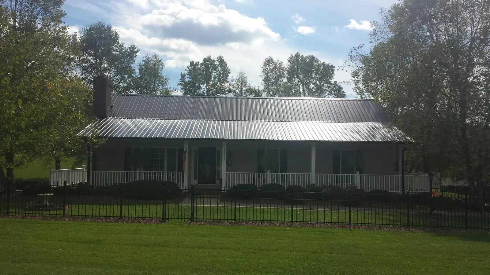 Gray metal roof on a brick ranch with a full width front porch — Gutter Guard Installation work by our crew in Corsicana
