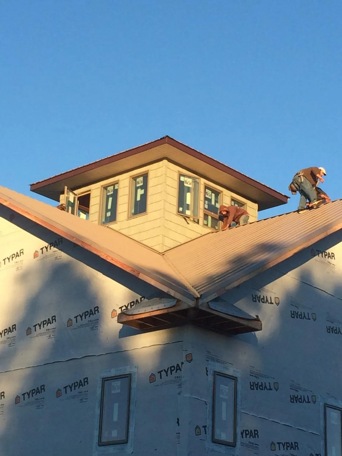 Roofers working around a rooftop cupola on a new metal roof at sunset — Roof Waterproofing in Corsicana by Roofing Brothers